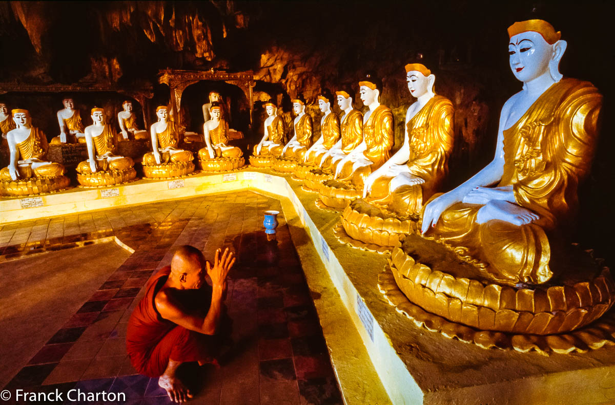 Moine en respect devant les bouddhas dorés à la feuille dans la grotte de Kawgun