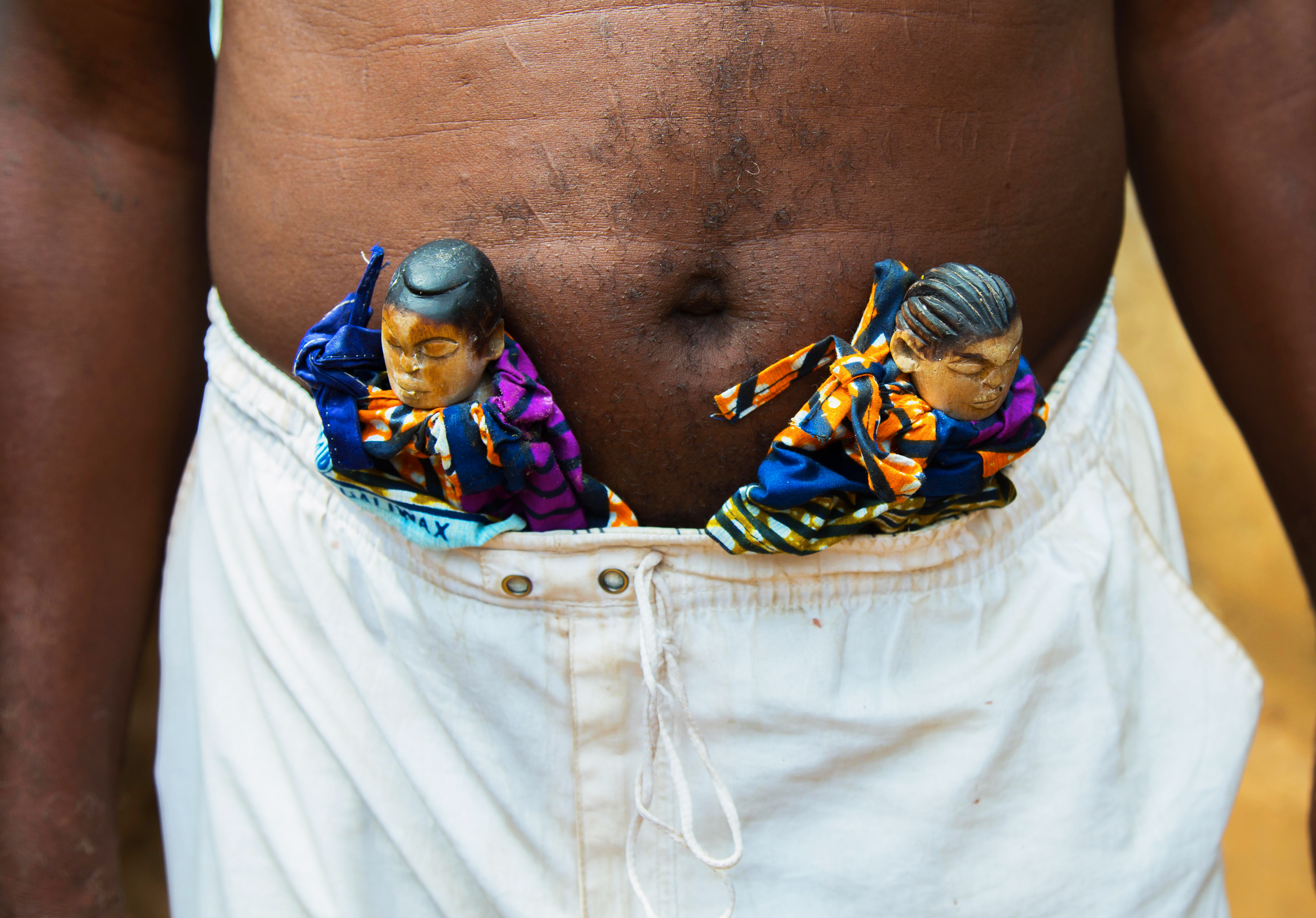 Au Bénin, un homme porte le tofa, figures en bois sculpté, pour accueillir l'âme de son jumeau défunt 