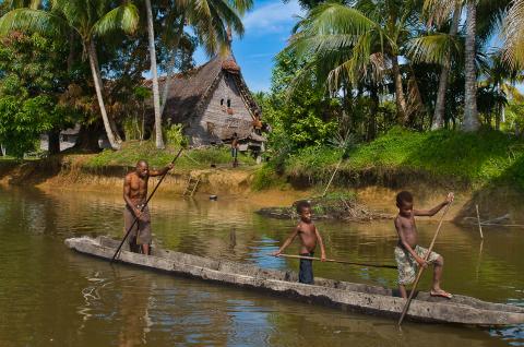 Pirogue sur le fleuve Sepik en Papouasie-Nouvelle-Guinée Rencontre d'une pirogue sur le fleuve Sepik devant la maison des esprits du village de Kabriman