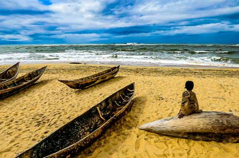 Rencontre avec une enfant contemplant une barque sur l'Océan indien dans la province de Tamatave