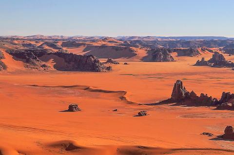 Trek sur un plateau de dunes ocres et hautes falaises dans la Tadrart