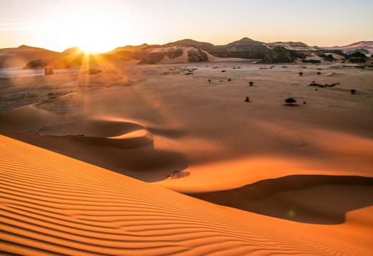 Trek dans les dunes de la Tadrart au soleil couchant en Algérie