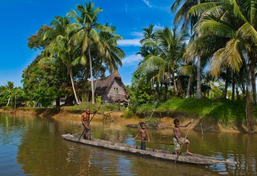 Rencontre d'une pirogue sur le fleuve Sepik devant la maison des esprits du village de Kabriman