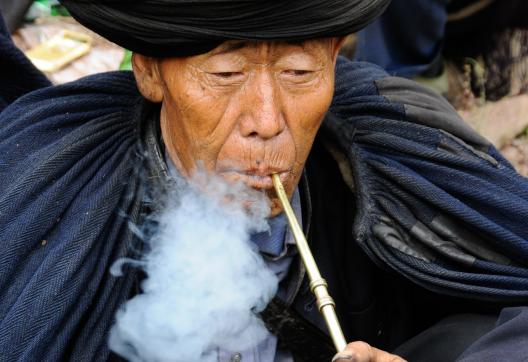 Randonnée vers un homme yi avec cape et pipe dans les Grandes Montagnes Froides