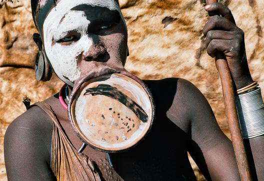 Marche vers une femme Surma devant sa case dans le sud ouest de l'Éthiopie