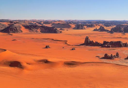 Trek sur un plateau de dunes ocres et hautes falaises dans la Tadrart