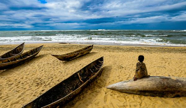 Enfant contemplant une barque sur l'Océan indien à Madagascar