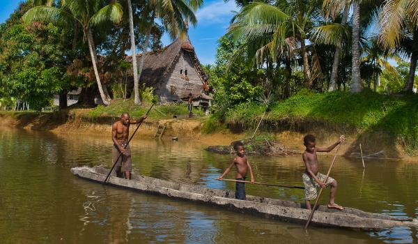 Rencontre d'une pirogue sur le fleuve Sepik devant la maison des esprits du village de Kabriman