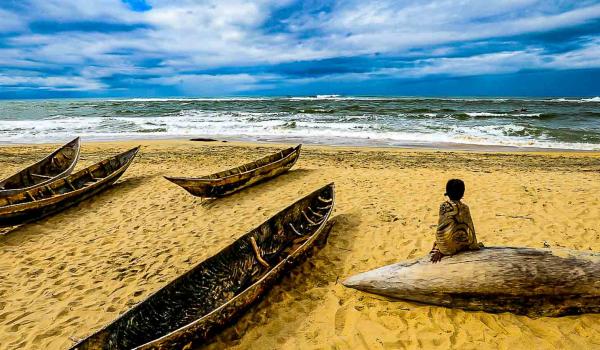 Rencontre avec une enfant contemplant une barque sur l'Océan indien dans la province de Tamatave