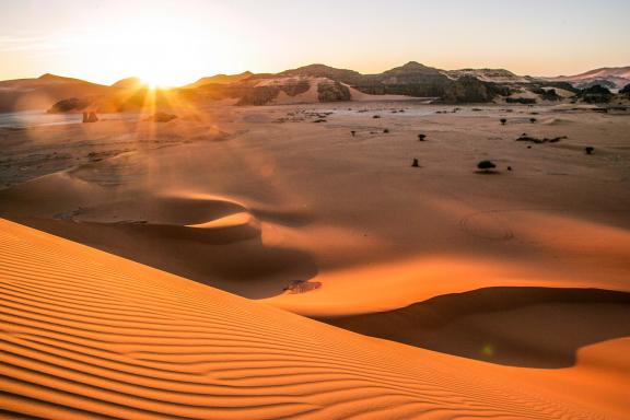 Trek dans les dunes de la Tadrart au soleil couchant en Algérie