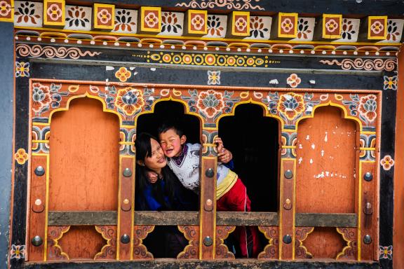 Mère et fils à la fenêtre d’une maison traditionnelle au Bhoutan