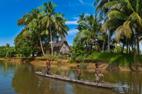 Rencontre d'une pirogue sur le fleuve Sepik devant la maison des esprits du village de Kabriman