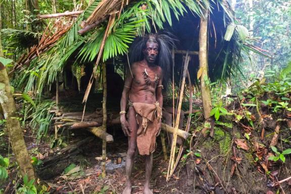 Trek vers un papou burati devant son abri de jungle près de la rivière Wapoga