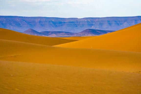Trekking sur des dunes devant un massif dans la vallée du Drâa