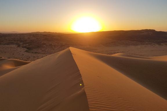 Voyage lors du coucher de soleil sur une dune dans le Hoggar